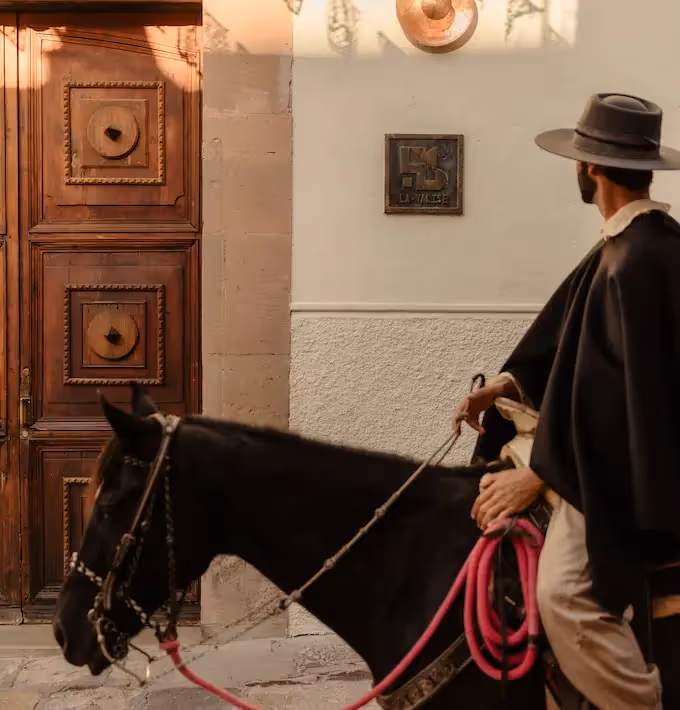 Traditional horse rider in front of the historic entrance of La Valise San Miguel Hotel, showcasing San Miguel de Allende's local culture.