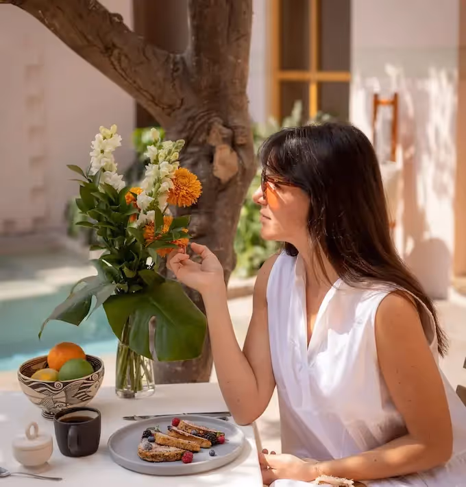 A woman enjoying breakfast on the patio at La Valise San Miguel Hotel restaurant, featuring fresh flowers and gourmet breakfast dishes.