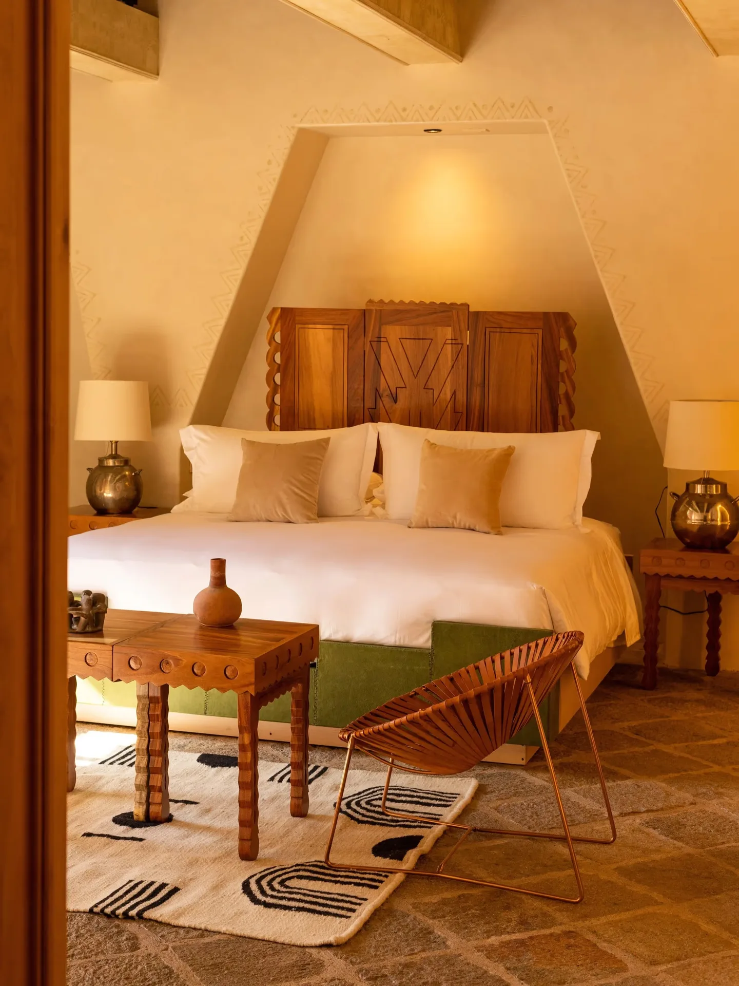 Lujosa suite de huéspedes con cama king size, cabecera de madera artesanal y cálido mobiliario de diseño en La Valise San Miguel Hotel.