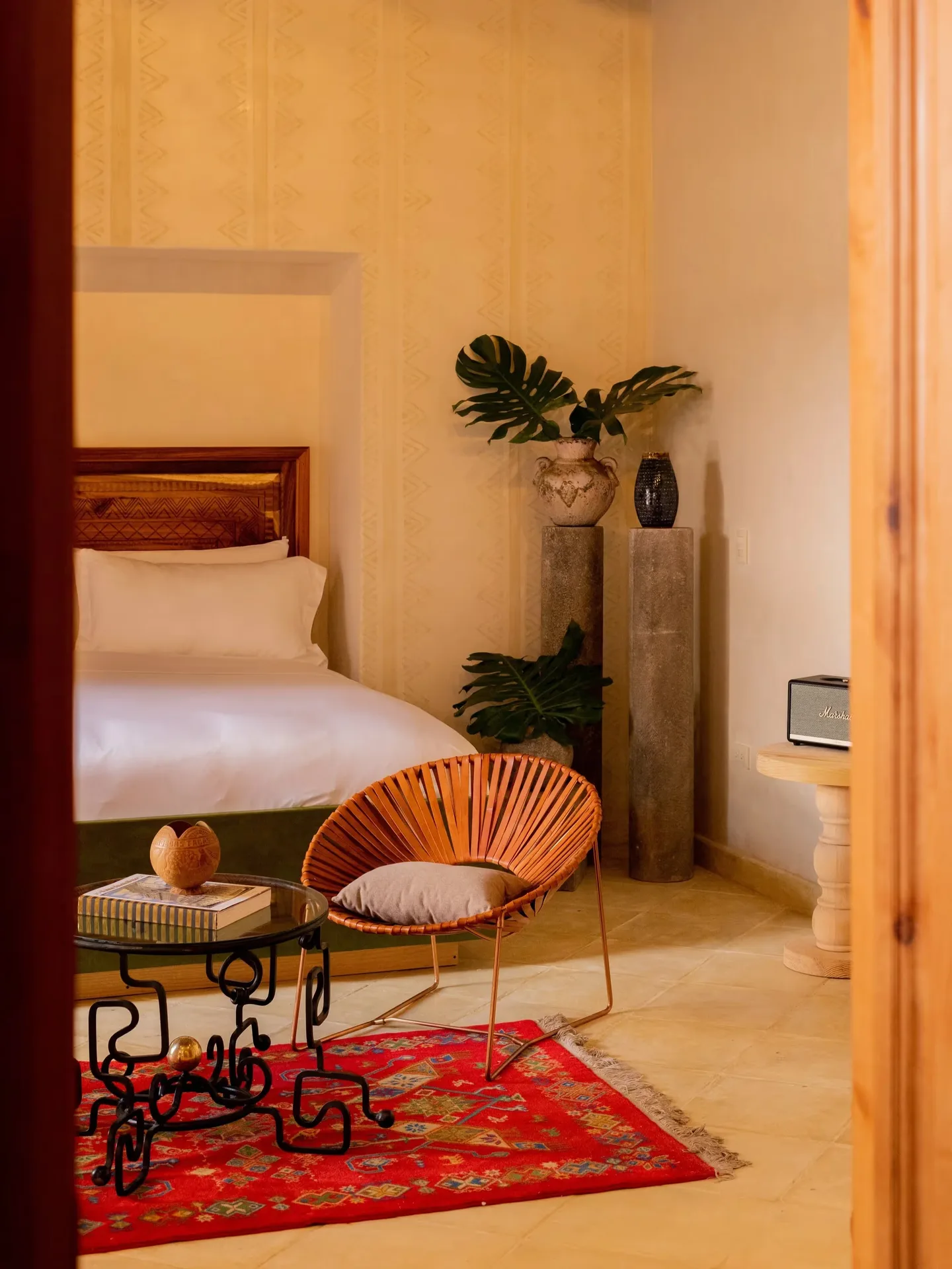 Elegant guest suite with a traditional red rug, wicker chair, and Mexican design accents at La Valise San Miguel Hotel.