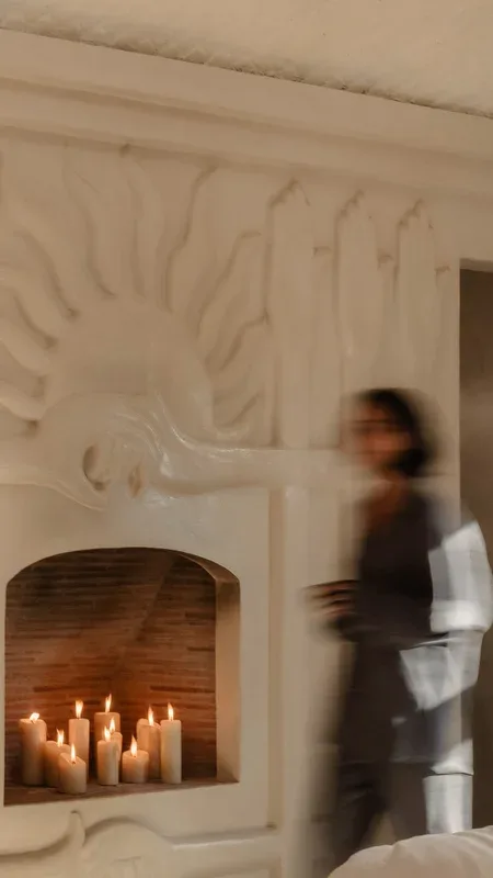 Guest walking past a candle-lit sculpted fireplace — Nurture stream of The Voyage Within