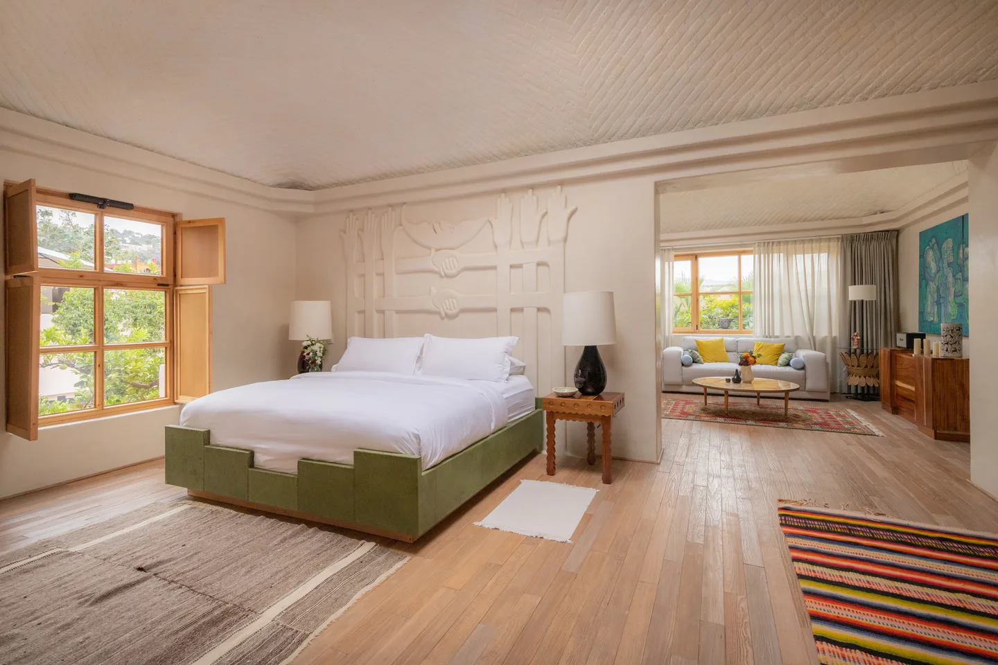 Master Suite bedroom with king bed, carved plaster relief wall and open view to the living room — La Valise San Miguel de Allende