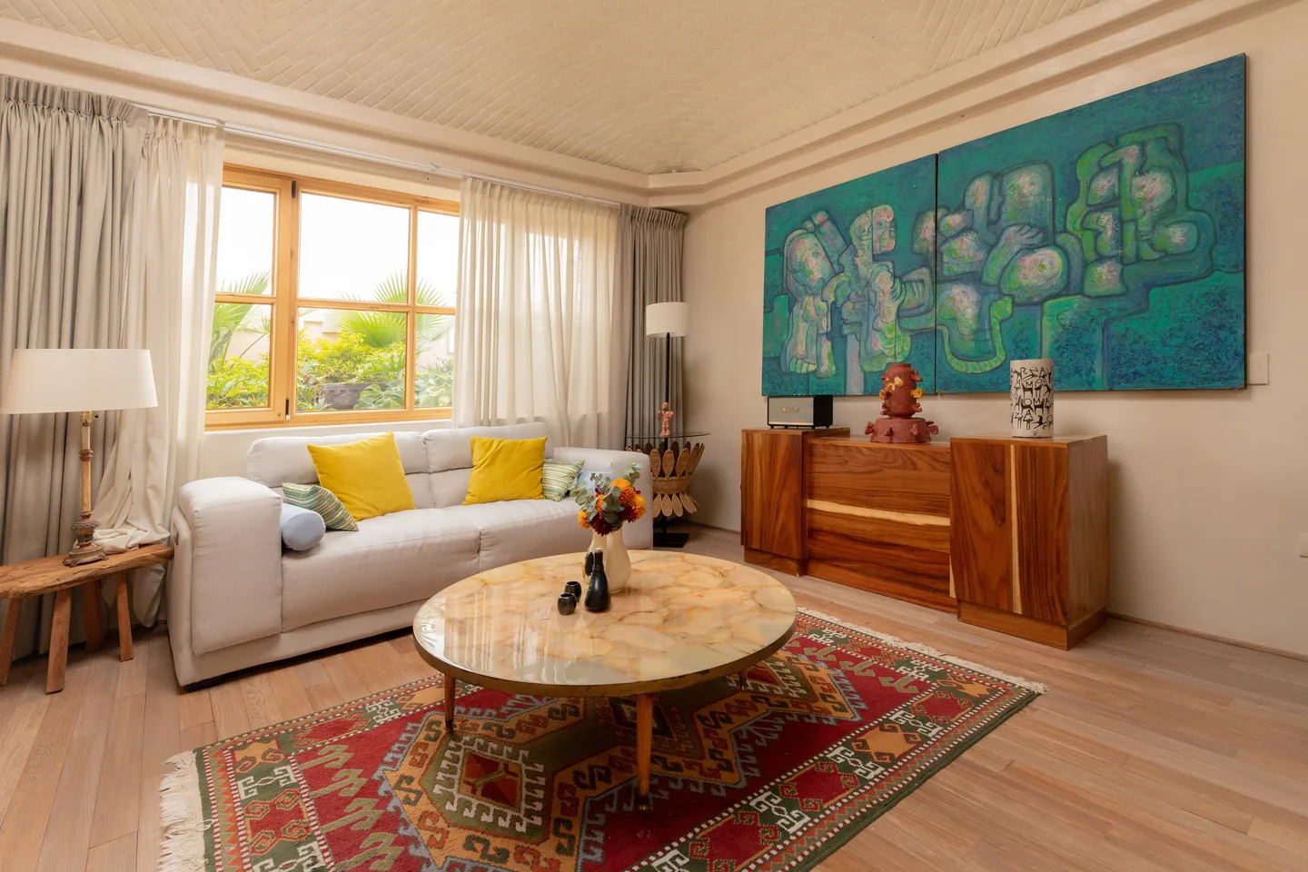 Sala de la Master Suite con sofá, mesa de centro de ónix y una gran obra de arte en tonos turquesa — La Valise San Miguel de Allende