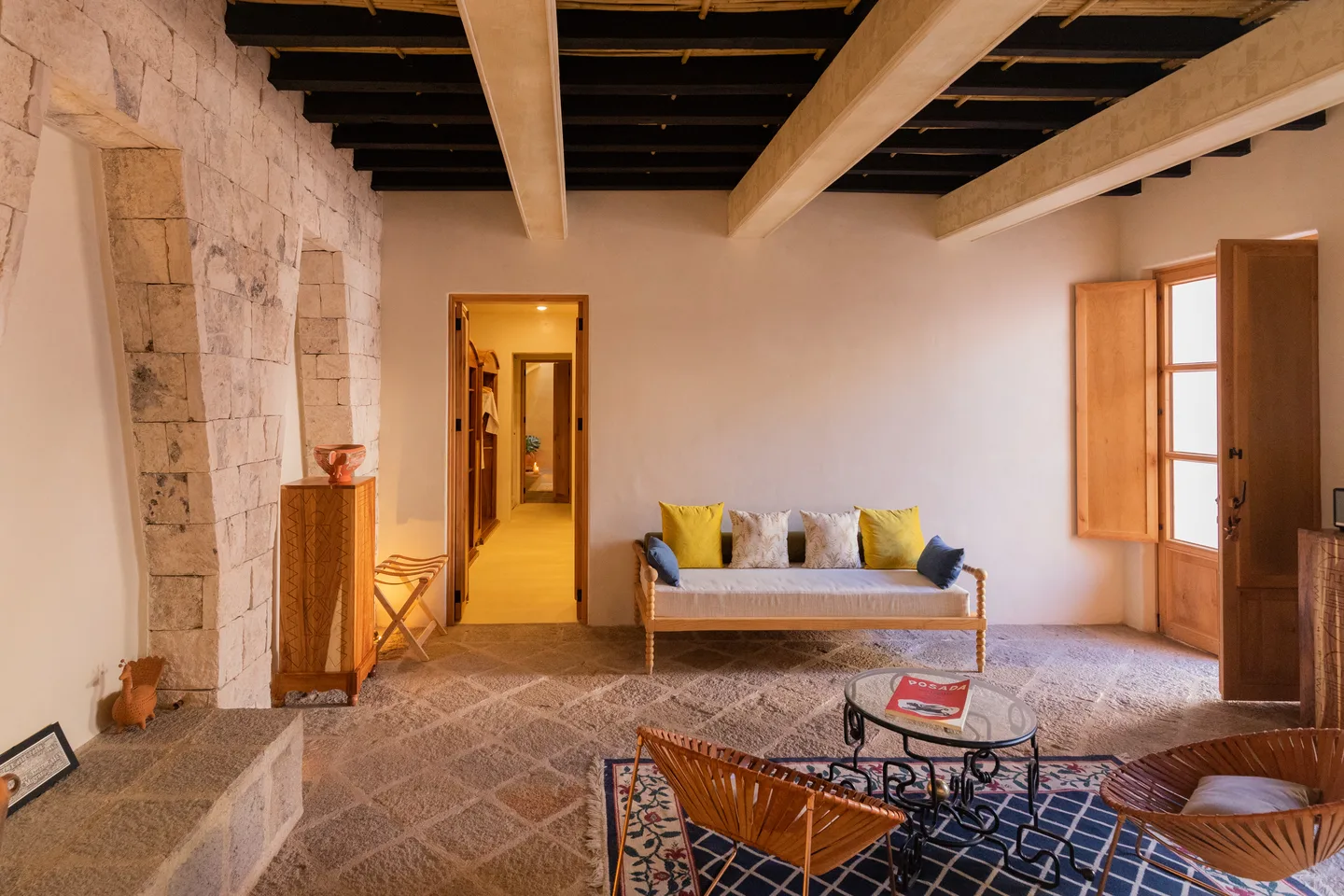Sala de estar de la Genesis Suite con sofá, sillas de piel y paso al baño — La Valise San Miguel de Allende