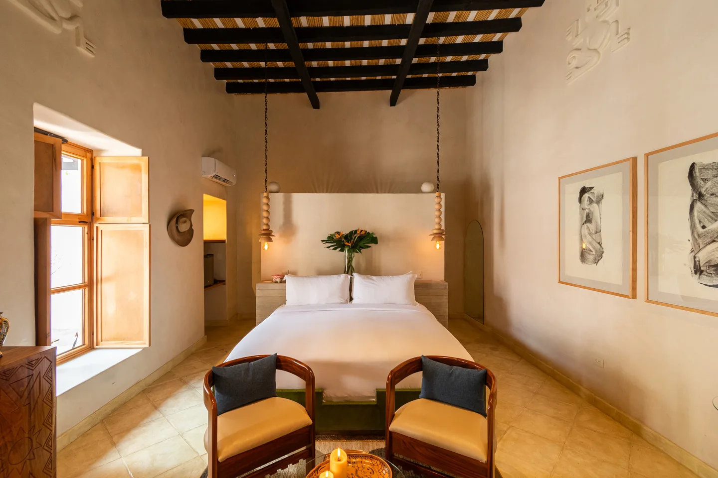 Recámara de Alma Suite con sillones al pie de la cama y techo de vigas de madera oscura — La Valise San Miguel de Allende