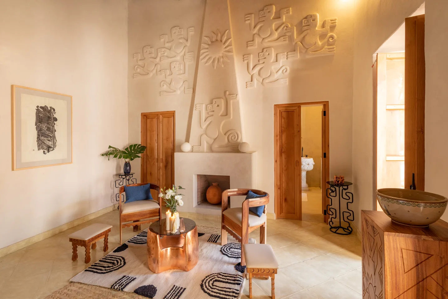 Área de estar con mesa de cobre y tapete gráfico frente a la chimenea esculpida en Alma Suite — La Valise San Miguel de Allende