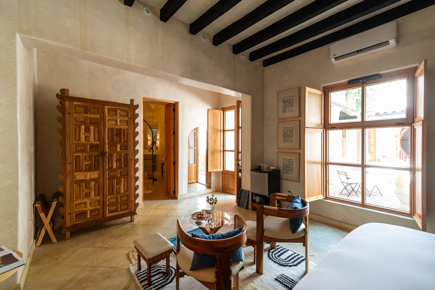 Área de estar de la Ollín Suite con armario tallado y gran ventanal hacia la terraza — La Valise San Miguel de Allende