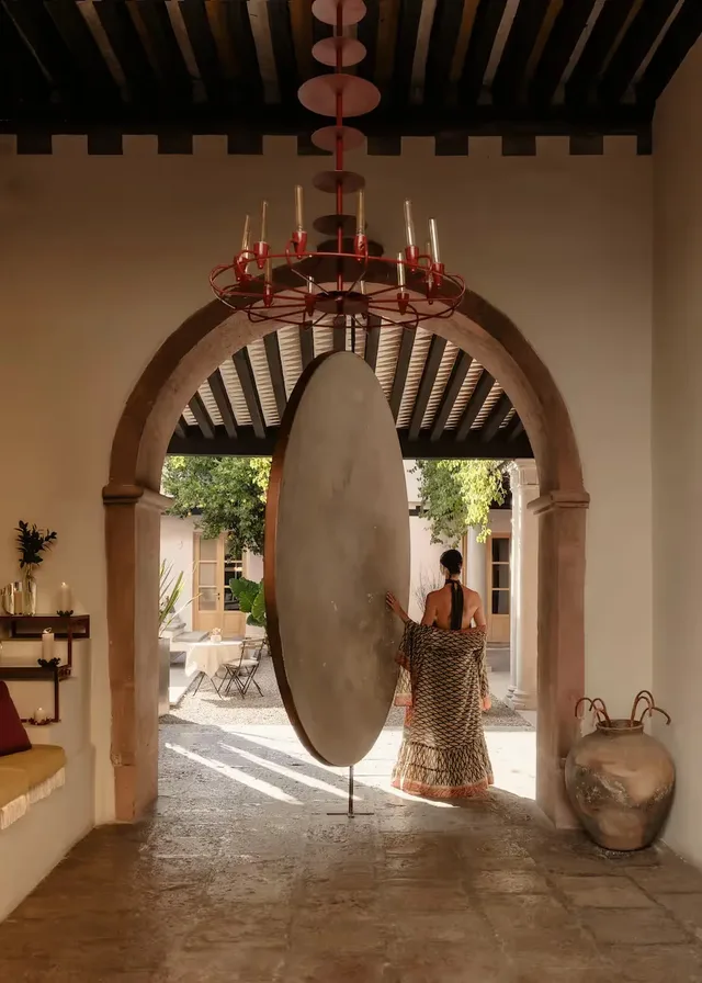 Monumental circular pivot “moon door” opening onto the sunlit courtyard at La Valise San Miguel de Allende