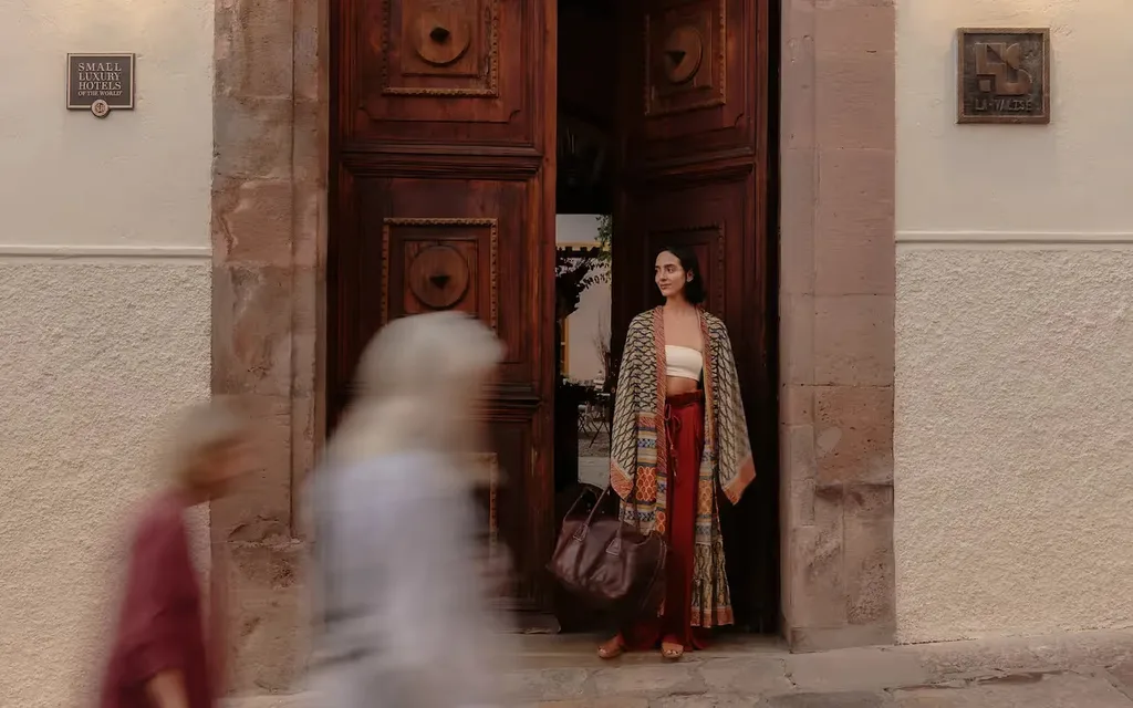 Guest in a colorful kimono at the carved wooden doors of the colonial facade at La Valise San Miguel de Allende