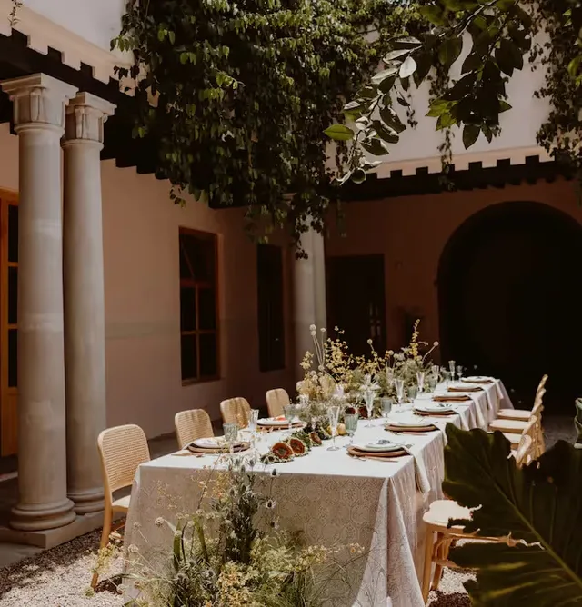 Long banquet table set among stone columns in the colonial courtyard at La Valise San Miguel de Allende