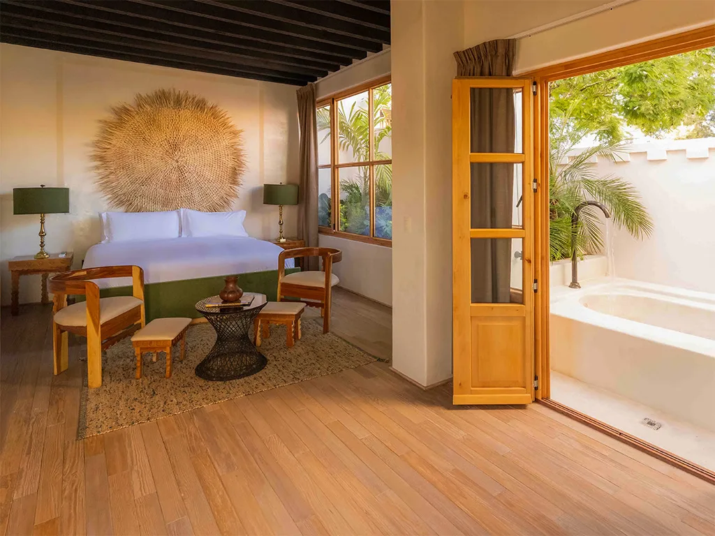 AURA SUITE — La Valise San Miguel: Bedroom with wooden floor, bed, and open door to a patio.